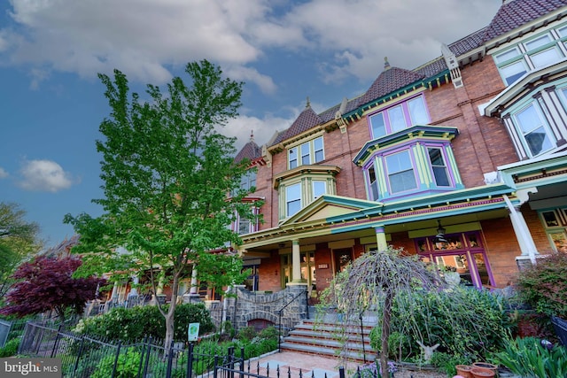 2636 N Calvert St N, Baltimore, MD 21218 - view of front of property featuring covered porch, brick siding, fence, and a high end roof