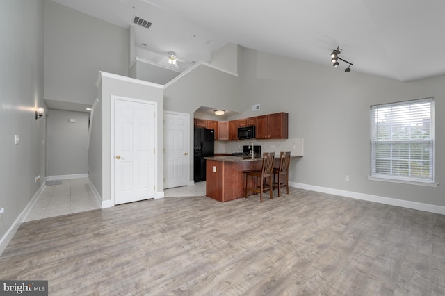 kitchen featuring a kitchen breakfast bar, a peninsula, open floor plan, visible vents, and black appliances
