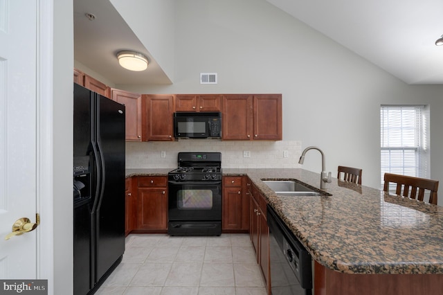 kitchen featuring a sink, dark stone counters, a peninsula, backsplash, and black appliances