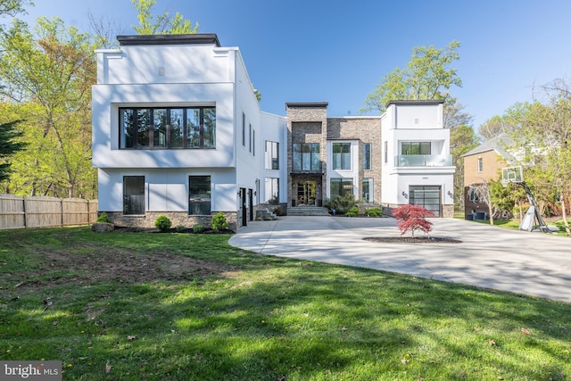 rear view of house featuring stone siding, stucco siding, and a balcony