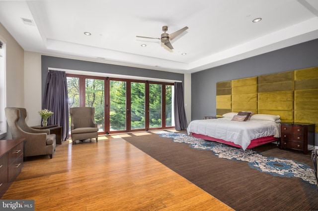 bedroom with a raised ceiling, wood finished floors, and recessed lighting