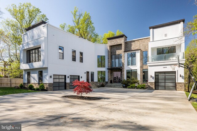 view of front of house with stone siding, stucco siding, an attached garage, and concrete driveway