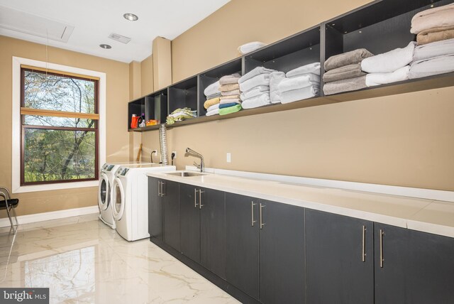 clothes washing area featuring cabinet space, light marble finish floors, washer and clothes dryer, attic access, and baseboards