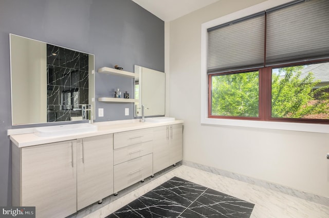 full bathroom with marble finish flooring, double vanity, and baseboards
