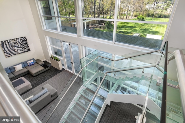 living area with french doors, a towering ceiling, and view of scattered trees