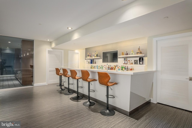 indoor dry bar featuring dark wood finished floors, baseboards, and recessed lighting