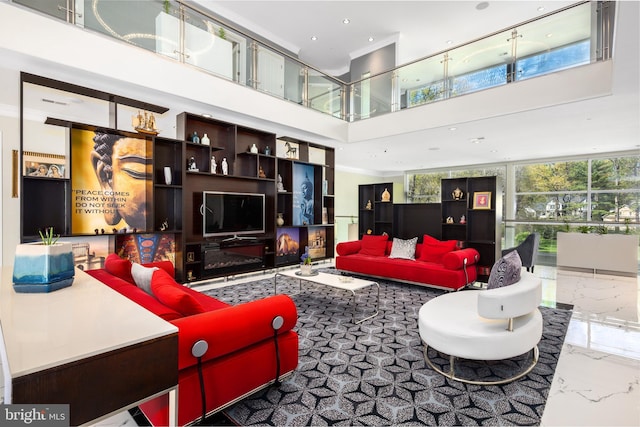living area featuring a towering ceiling, marble tiled flooring, recessed lighting, and crown molding