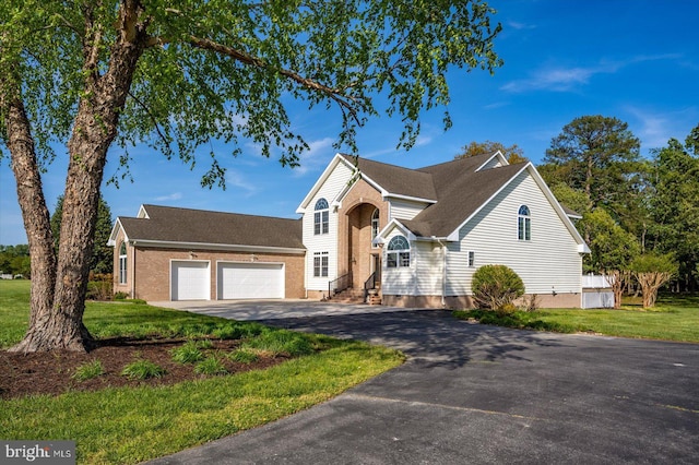 traditional home with an attached garage, aphalt driveway, and a front yard