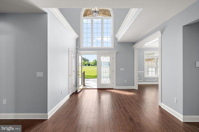entrance foyer with dark wood-type flooring, ornamental molding, baseboards, and a chandelier