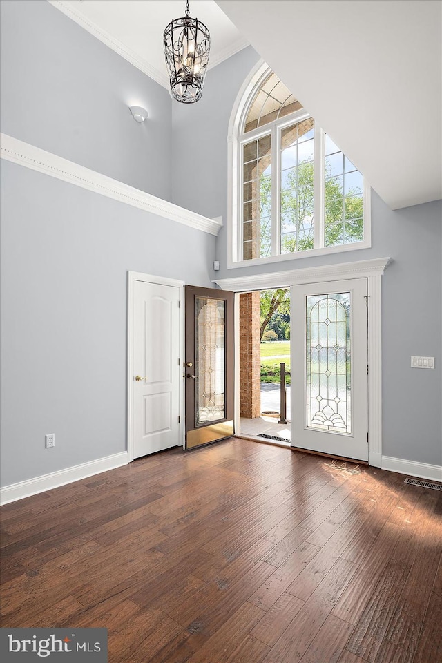 entrance foyer featuring baseboards, a towering ceiling, a chandelier, and a wealth of natural light