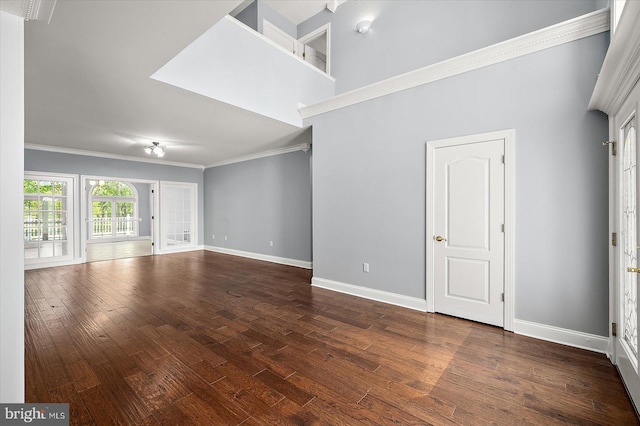 unfurnished living room featuring dark wood-type flooring, baseboards, and crown molding