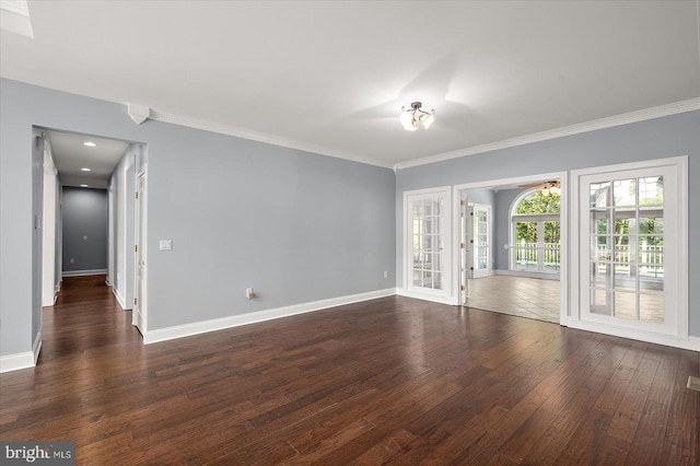empty room featuring baseboards, ornamental molding, and dark wood finished floors