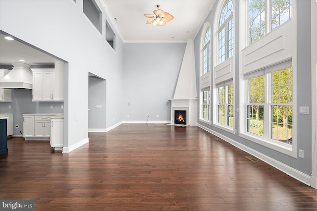 unfurnished living room featuring a fireplace with flush hearth, a high ceiling, plenty of natural light, and visible vents