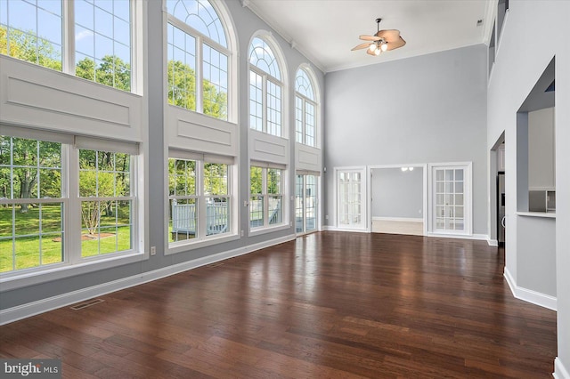 unfurnished living room featuring visible vents, ornamental molding, a towering ceiling, wood finished floors, and ceiling fan