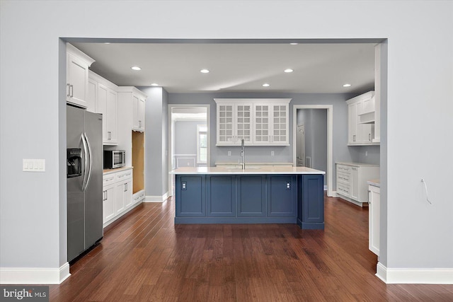 kitchen featuring dark wood-style flooring, appliances with stainless steel finishes, a sink, baseboards, and white cabinetry