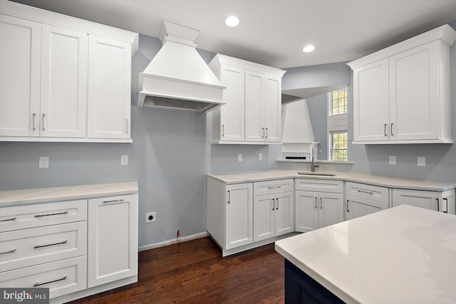 kitchen with a sink, white cabinets, custom range hood, and dark wood finished floors
