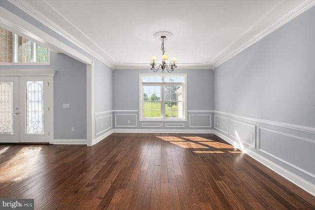 unfurnished dining area featuring crown molding, an inviting chandelier, wainscoting, and hardwood / wood-style floors