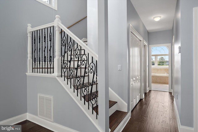stairway with baseboards, wood finished floors, and visible vents