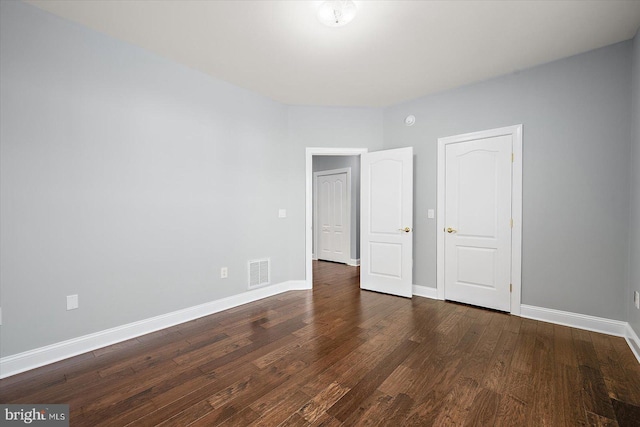 unfurnished bedroom featuring baseboards, visible vents, and wood finished floors