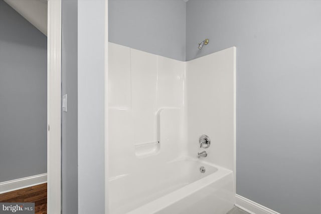 bathroom featuring baseboards,  shower combination, and wood finished floors