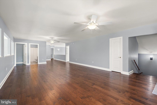 unfurnished living room with dark wood-type flooring, a ceiling fan, and baseboards