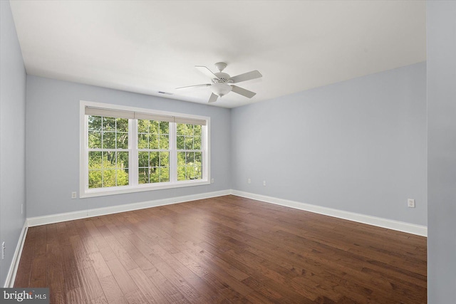 spare room with a ceiling fan, baseboards, visible vents, and dark wood finished floors