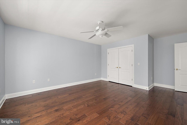 unfurnished bedroom featuring baseboards, dark wood finished floors, and a closet