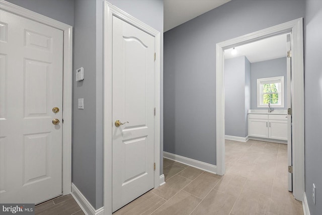 corridor featuring baseboards and a sink