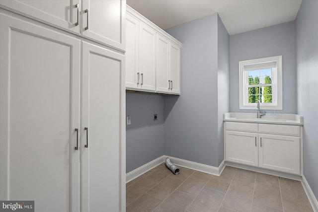 laundry area with baseboards, a sink, cabinet space, light tile patterned floors, and hookup for an electric dryer
