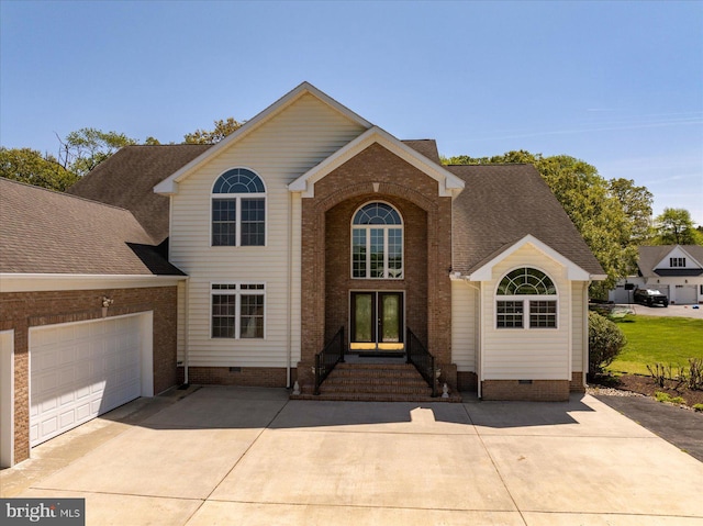 traditional home with a garage, driveway, brick siding, and crawl space