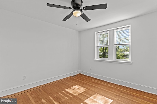 empty room featuring baseboards, ceiling fan, wood finished floors, and visible vents