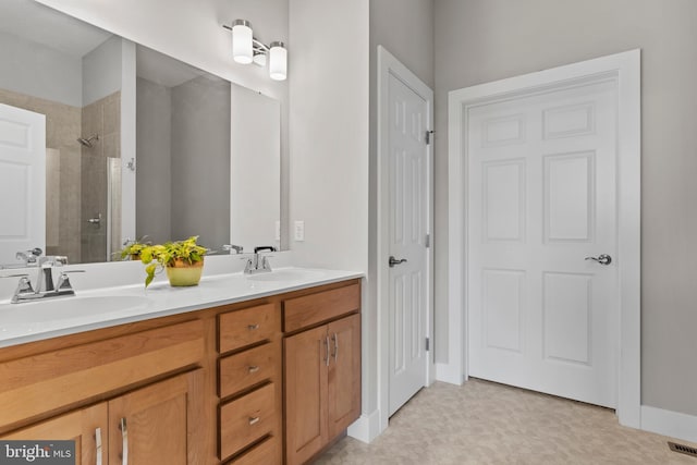 full bath featuring a sink, tile patterned floors, double vanity, and tiled shower