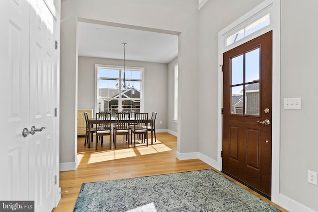 entrance foyer featuring baseboards, a chandelier, and light wood finished floors