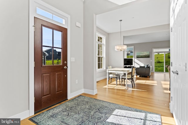 foyer with baseboards, wood finished floors, and a chandelier