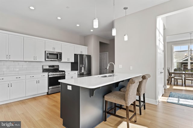 kitchen featuring a peninsula, a breakfast bar area, tasteful backsplash, a sink, and appliances with stainless steel finishes