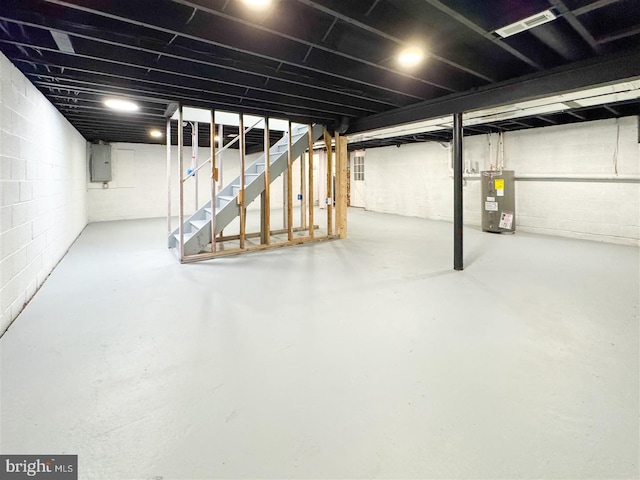 unfinished below grade area featuring visible vents, water heater, electric panel, and stairway