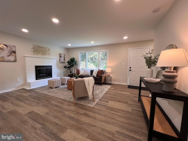 living area featuring a brick fireplace, recessed lighting, baseboards, and dark wood-style floors