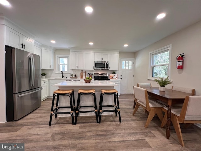 kitchen featuring a sink, appliances with stainless steel finishes, white cabinets, and light countertops