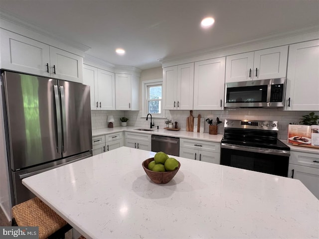 kitchen with stainless steel appliances, light stone countertops, a sink, and tasteful backsplash