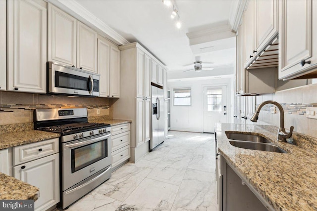 kitchen featuring stainless steel appliances, a sink, backsplash, a ceiling fan, and light stone counters