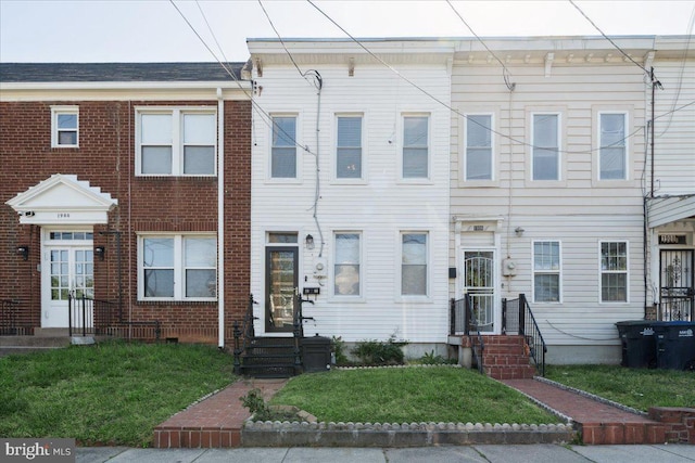 view of property featuring a front yard, entry steps, and brick siding