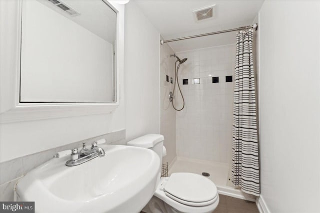 full bath featuring a sink, toilet, and a shower stall