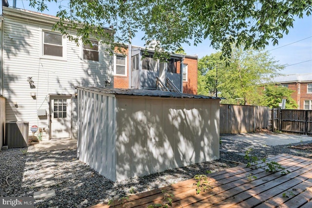 back of house featuring a fenced backyard, central AC, a wooden deck, an outdoor structure, and a storage shed
