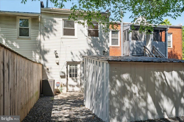 rear view of property with fence and central AC