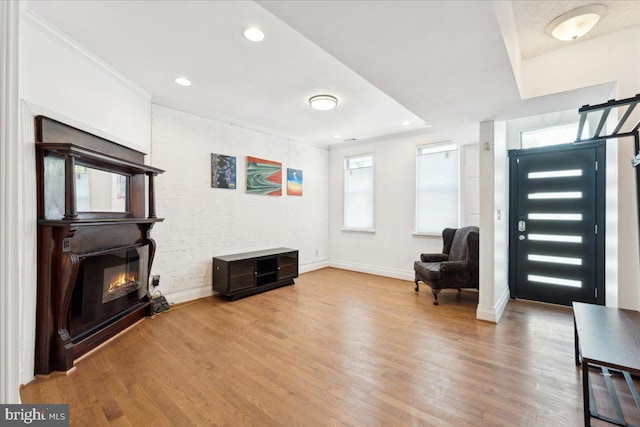 sitting room with a glass covered fireplace, wood finished floors, baseboards, crown molding, and recessed lighting