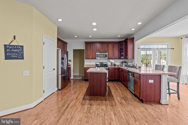 54 Durham Ln, Smyrna, DE 19977 - kitchen featuring stainless steel appliances, a peninsula, light wood-type flooring, a breakfast bar area, and glass insert cabinets