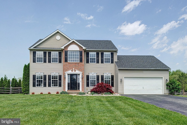 colonial home with a garage, a front lawn, aphalt driveway, fence, and a shingled roof