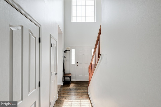 entrance foyer featuring dark wood-type flooring, stairs, and a towering ceiling