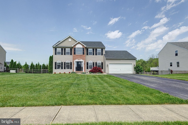 colonial inspired home with fence, aphalt driveway, a front lawn, and a garage