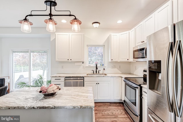 kitchen with recessed lighting, white cabinets, a sink, light wood-style flooring, and stainless steel appliances